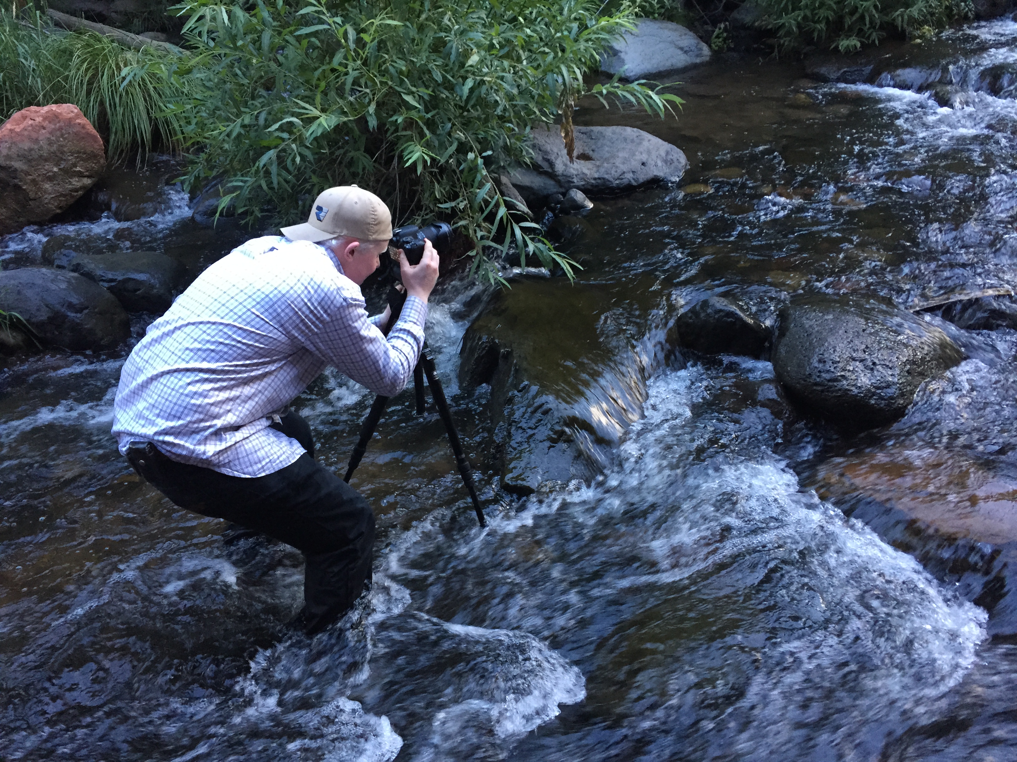 Wayne shooting photography in a stream